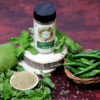 Pahadi Chaat Masala in a bottle and a small bowl, with raw green chilies and mint leaves nearby, emphasizing the contrast between the spice blend and its natural ingredients.