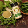 Pahadi Chaat Masala in a bottle and a small bowl, with raw green chilies , cumin seeds and mint leaves nearby, emphasizing the contrast between the spice blend and its natural ingredients."