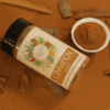 A bottle filled with cinnamon powder, accompanied by raw cinnamon sticks placed beside it, showcasing the ground spice and its natural source