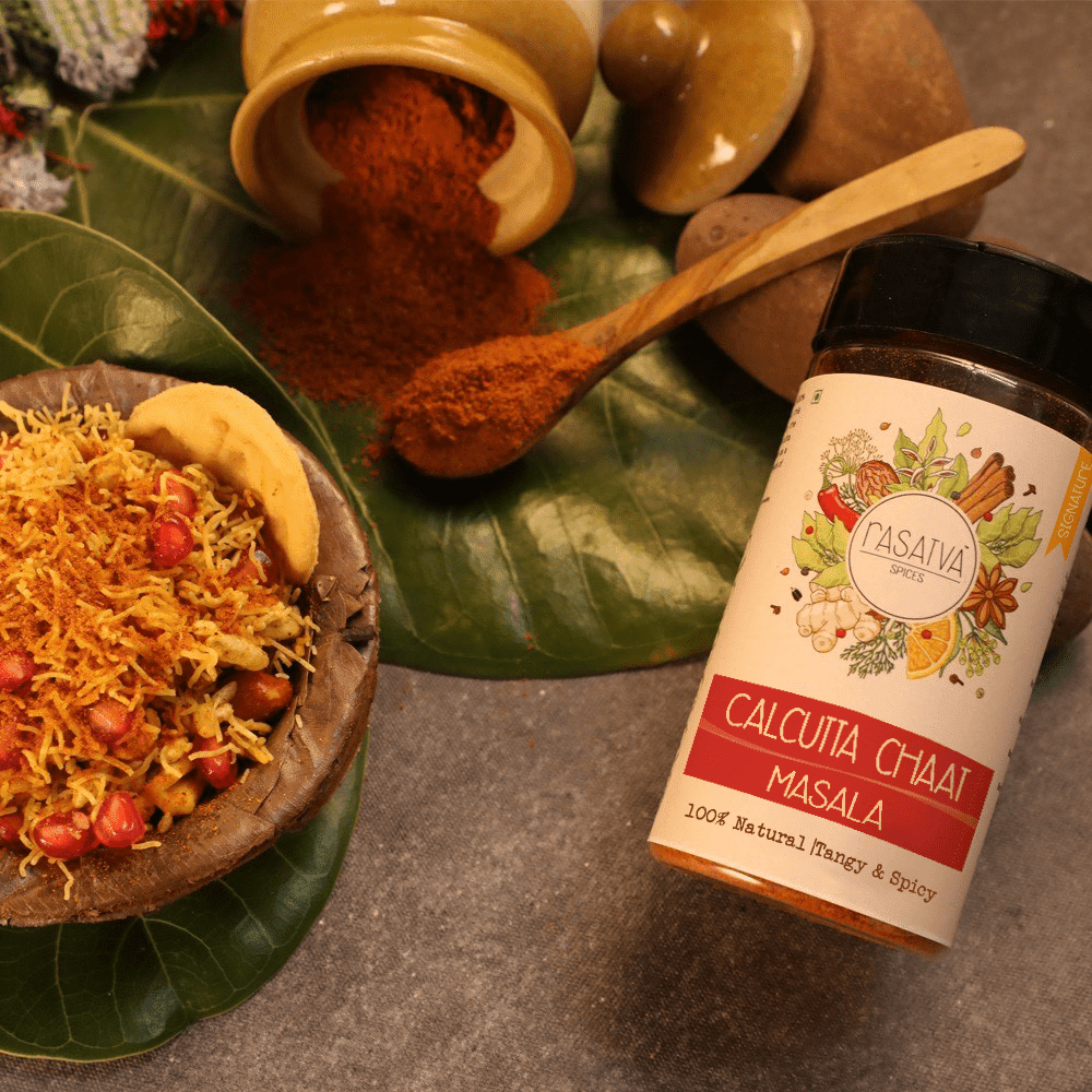 "Calcutta Chaat Masala in a bottle, with seasoning on a spoon and spread over chaat, emphasizing the spice blend's use and its impact on chaat dishes.