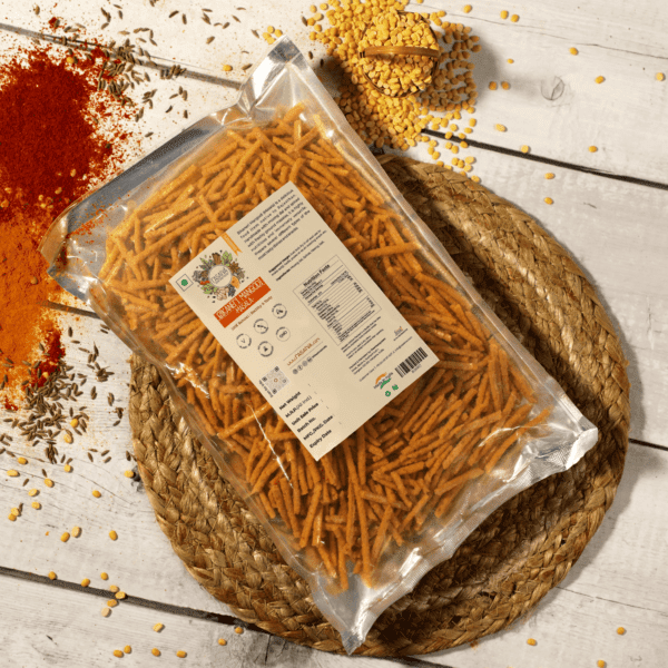"Bikaneri Mangodi Masala in a packet, with some of the masala shown and cumin seeds positioned at the back, highlighting the seasoning blend and its key ingredient