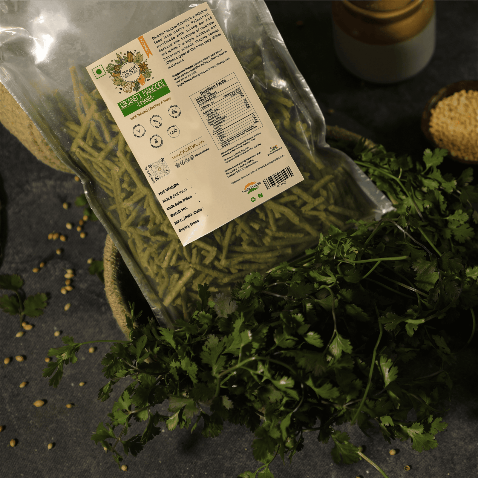 Bikaneri Mangodi Dhania in a packet, with some of the product displayed alongside coriander seeds and leaf, highlighting the seasoning blend and its fresh ingredient